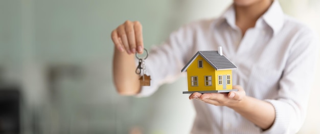 Обрезанный снимок агента по недвижимости, вручающего ключи и домашнюю модель