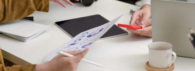 Cropped shot of start up partners working together on white table with digital devices and paper work