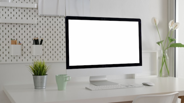 Cropped shot of stylish office room with blank screen computer, office supplies and decorations