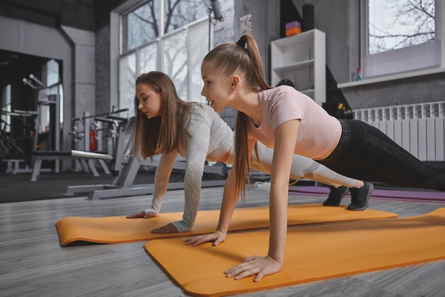 板の運動をしている10代の少女と彼女のパーソナルトレーナーのトリミングされたショット