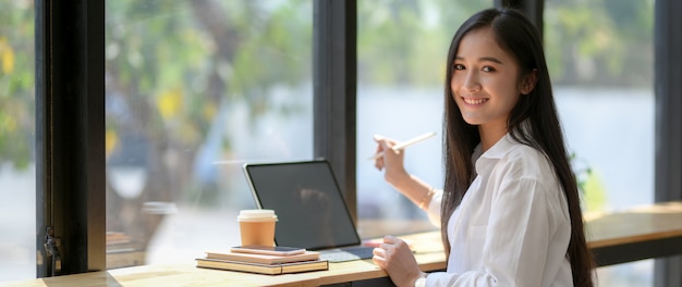 태블릿 작업하는 동안 커피 숍에 앉아 대학생의 자른 샷