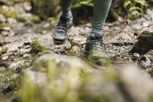 Cropped shot of an unrecognisable woman hiker crossing a stream while exploring in the woods.