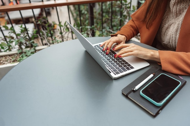 Обрезанный снимок женщины в кафе, работающей на ноутбуке.