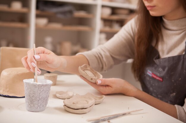 Photo cropped shot of a woman decorating pottery figurine at art studio