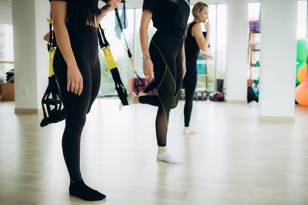 Cropped shot of woman doing fitness TRX training exercises at industrial gym Straps crossfit group workout concept Horizontal shot Selective focus High quality photo