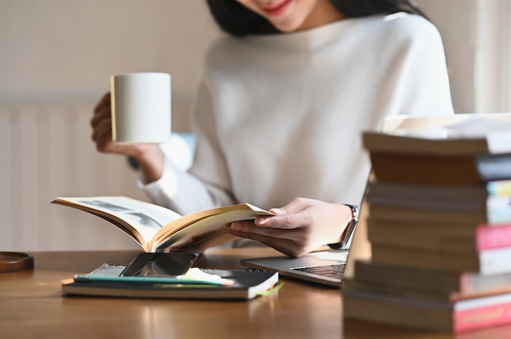 Photo 本を読みながらコーヒーカップを保持しているショット女性をトリミング