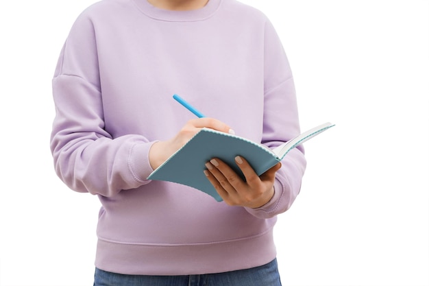 Cropped shot of a woman in a lavander oversized sweatshirt making notes in a notebook