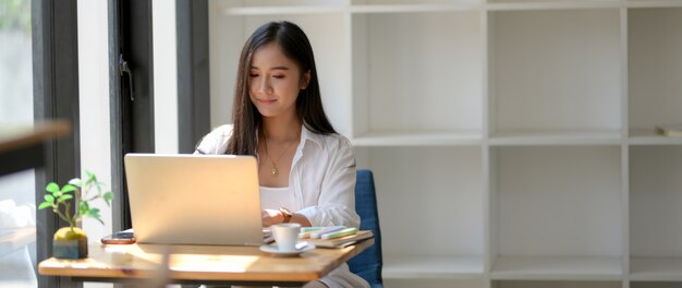 ノートパソコンでの彼女の仕事に焦点を当てた女性大学生のトリミングされたショット