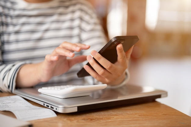 A cropped shot of a woman using her smartphone at a desk