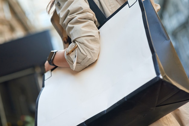 Cropped shot of woman with big shopping bag standing on city street. Fashion, people lifestyle concept