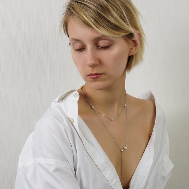 Photo cropped shot of young blonde woman with straight hair wearing silver chain with a pendant isolated on a gray background jewelry with gemstones holiday accessories