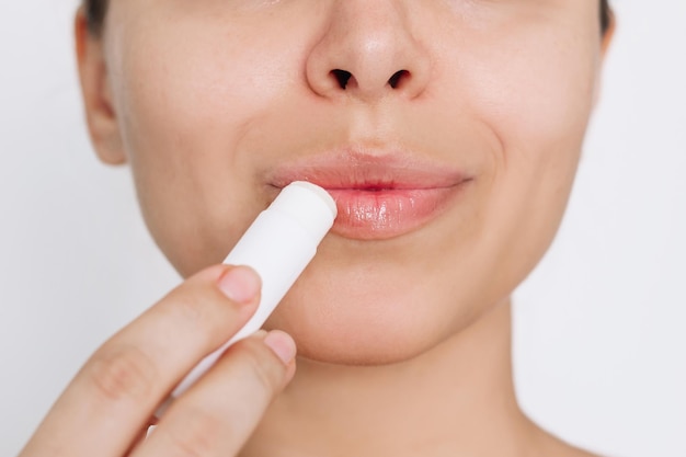 Cropped shot of a young caucasian attractive woman applying a hygienic lipstick on her lips
