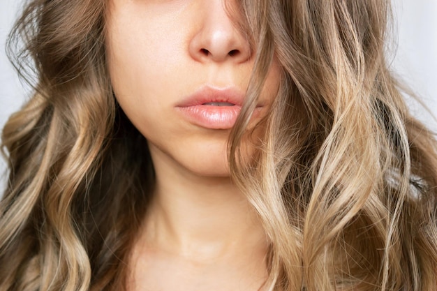 Cropped shot of a young caucasian blonde woman with wavy hair Result of coloring perming