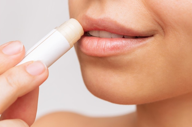 Cropped shot of a young caucasian pretty woman applying a hygienic lipstick on her lips