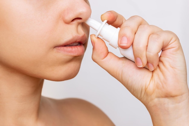 Cropped shot of a young caucasian woman using nasal spray for a runny nose and congestion