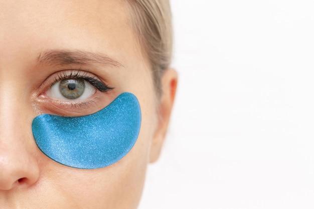 Cropped shot of a young caucasian woman with blue gel glittering patches on the skin under eyes