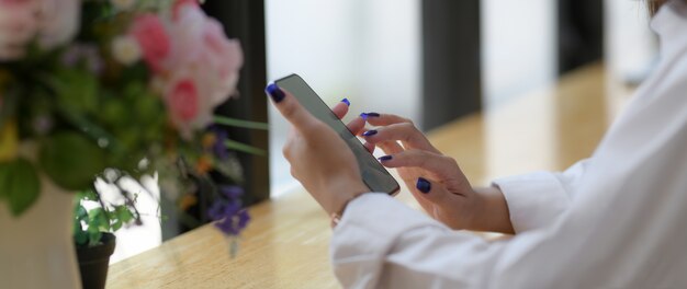 Cropped shot of young college student using smartphone on wooden counter bar