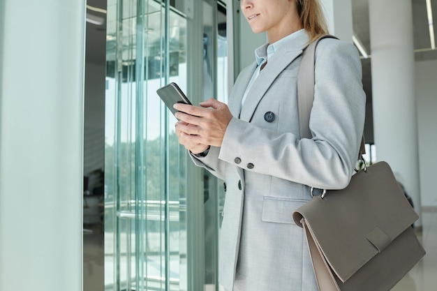 Cropped shot of young elegant woman with leather handbag on shoulder