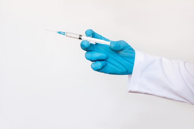 Cropped shot of young female doctor in a white coat holding a syringe with her hand in a blue glove