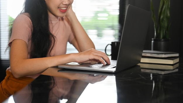 Ritagliata di giovane donna freelance che lavora a distanza da casa con un computer portatile