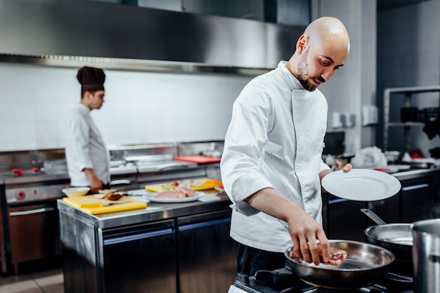 Colpo ritagliato di un giovane chef maschio che prepara la carne in una cucina professionale