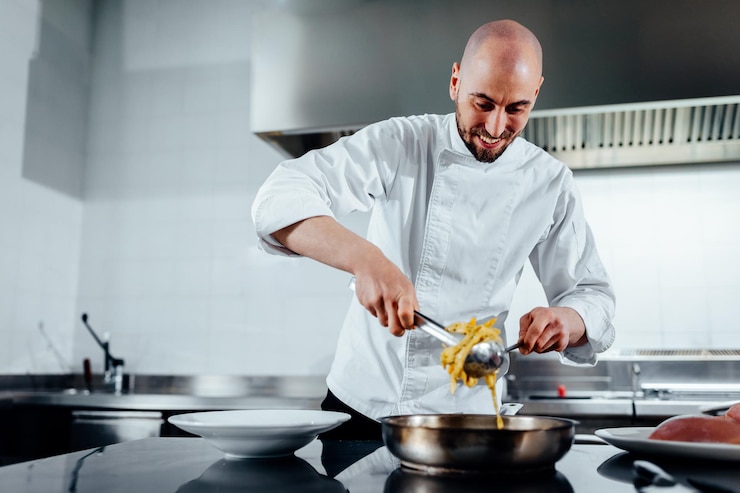 Photo cropped shot of a young male chef serving the food in a professional kitchen