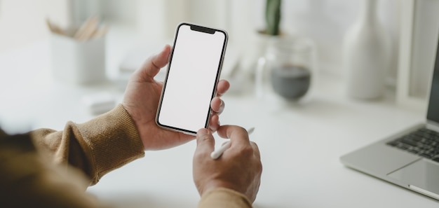 Cropped shot of young male freelancer holding blank screen smartphone