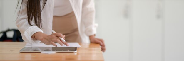 Cropped shot of young woman college student typing on digital tablet