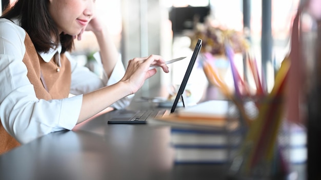 Cropped shot of young woman graphic designer sitting at creative office and working on digital tablet.