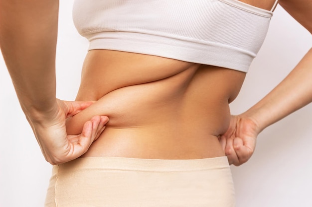 Cropped shot of a young woman holding fat folds on her back Overweight flabby and sagging muscles