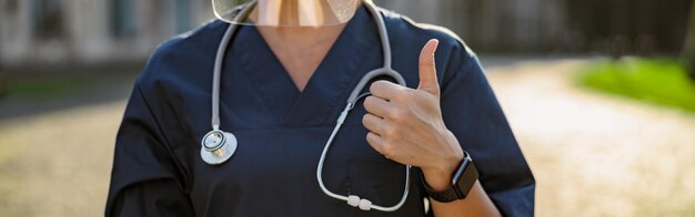 Cropped shot of young woman nurse in uniform wearing face shield and mask for safety to prevent