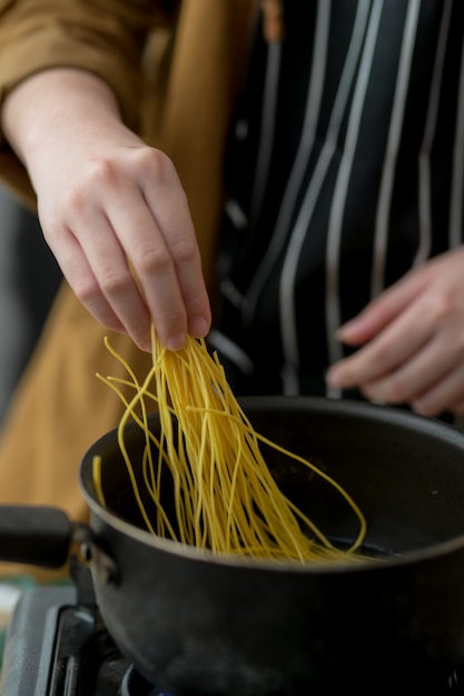 麺メニューの食材を準備する若い女性のショットをトリミング