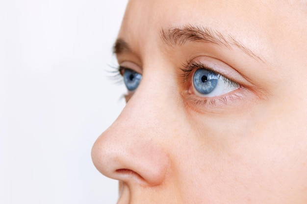 Colpo ritagliato del viso di una giovane donna con lenti blu isolate su sfondo bianco