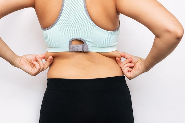 Cropped shot of a young woman in a sporty short top holding fat folds on her back Overweight