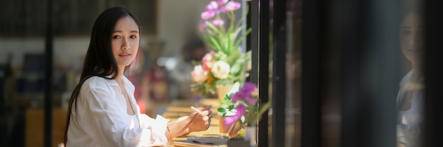 Cropped shot of young woman university student working on her assignment on counter bar