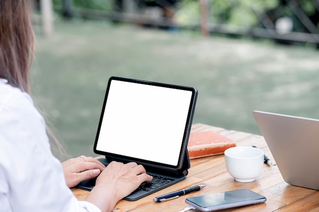 Cropped shot of young woman using tablet with keyboard, mockup blank screen for product display.