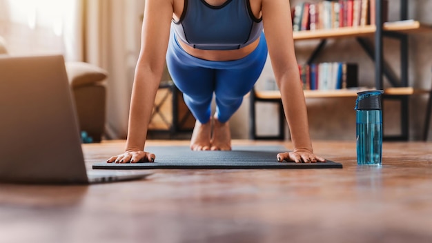 Cropped shot of young woman watching training videos on laptop
while exercising at home