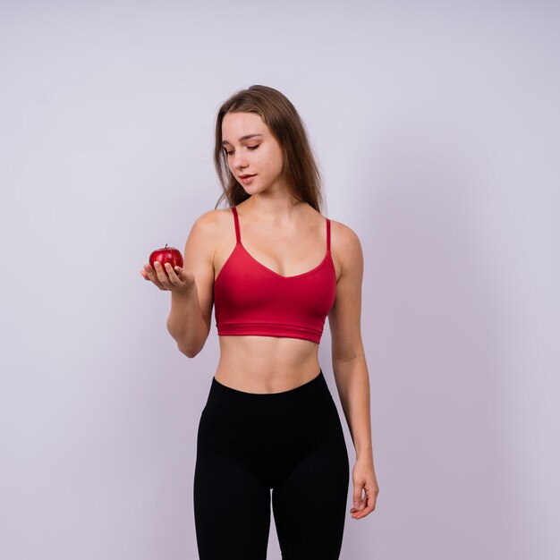 Cropped of sporty female with well fit body holding apple healthy food and fit body concept