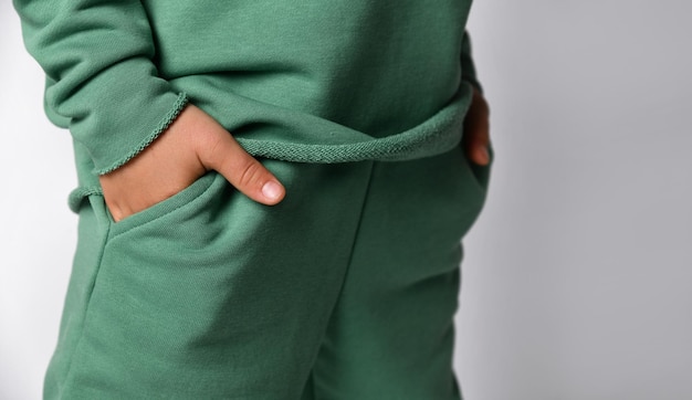 Foto ritratto in studio con la mano di un scolaro bambino in tasca di abbigliamento sportivo il ragazzo è vestito con abiti casuali frammento pubblicitario della foto teenage fashion and fashion style concept