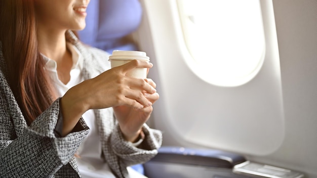 비행 중 뜨거운 커피를 홀짝이며 성공한 아시아 여성 사업가