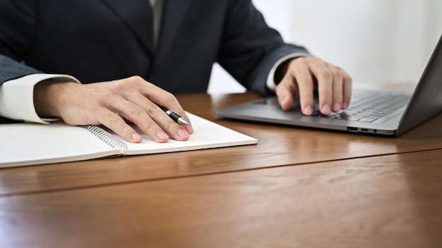 cropped successful businessman in formal suit working at his desk using laptop computer