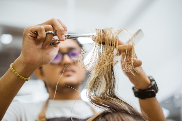 Foto vista ritagliata di un barbiere asiatico che taglia i capelli dei suoi clienti