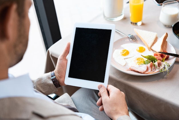 Photo cropped view of businessman holding digital tablet with blank screen in cafe