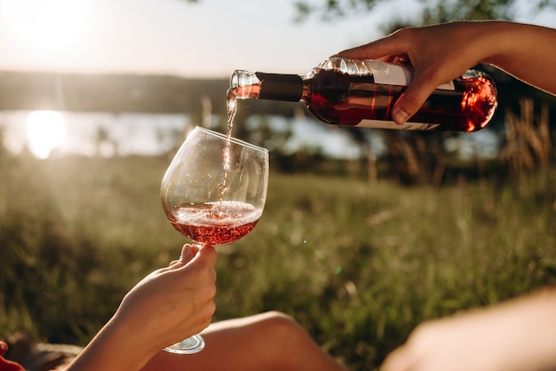 cropped view of couple pouring red wine on meadow