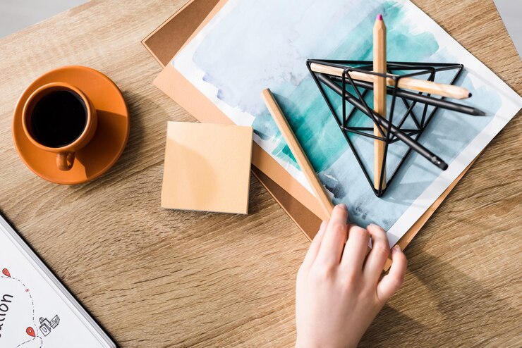 Photo cropped view of girl holding pencil on table near of cup of coffee sticky notes drawing and