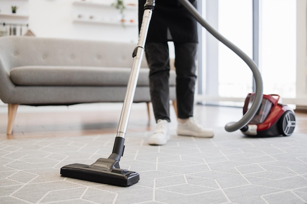 Cropped view of hands holding vacuum cleaner of female cleaning service worker