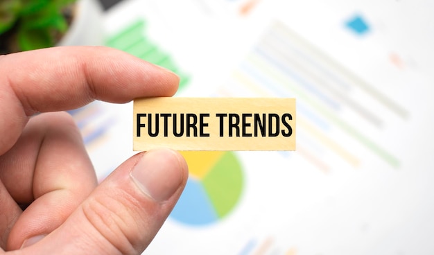 Photo cropped view of hands holding wooden cube with future trends lettering on work table. top view