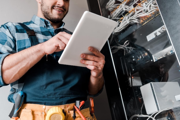 Photo cropped view of happy bearded technician using digital tablet