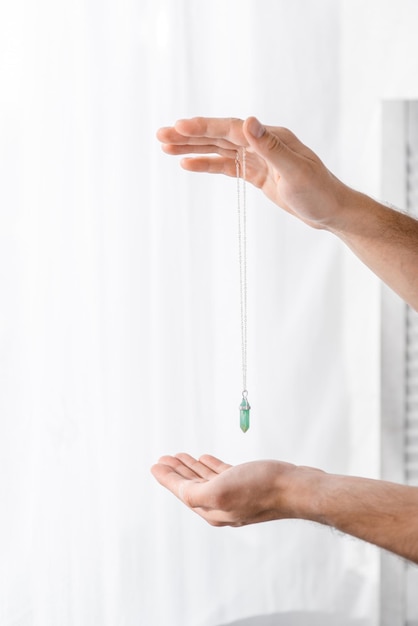 Cropped view of hypnotist holding green stone in clinic