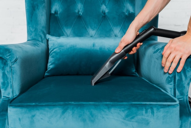 Cropped view of man cleaning blue armchair with vacuum cleaner